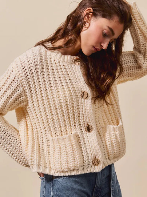 young woman wearing a longline beige chunky knit cardigan sweater
