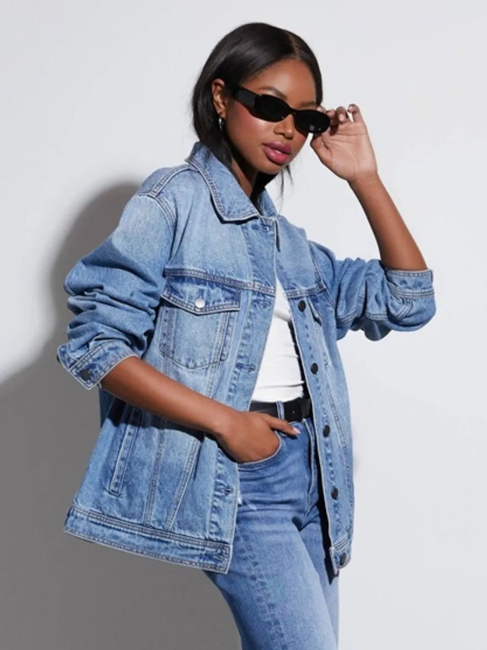 Woman wearing a loose fit denim jacket and jeans with sunglasses on