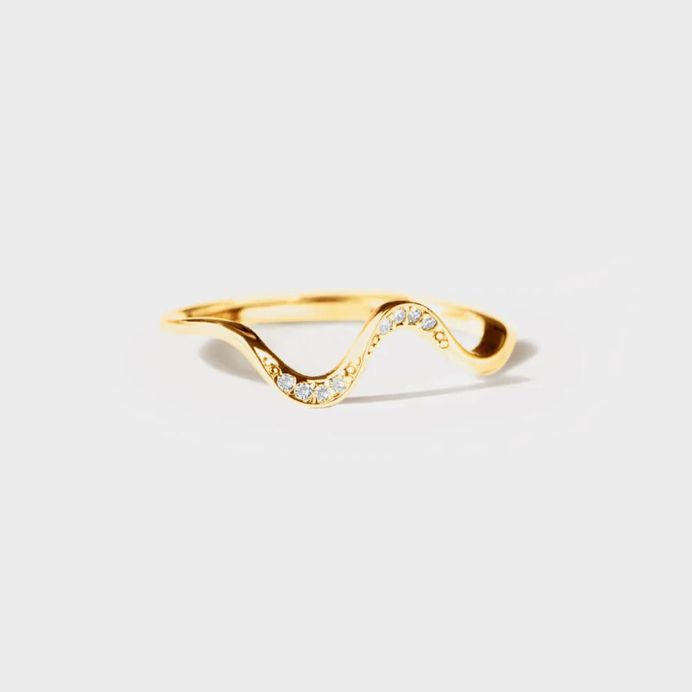 Gold ring with wavy design on a light gray background