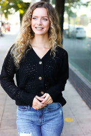Black sequined pointelle knit cardigan with gold buttons and distressed jeans