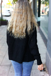 Black cable knit cardigan with glitter accents and pointelle details
