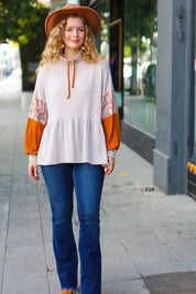Cream and orange boho lace-sleeve blouse with brown hat and blue jeans