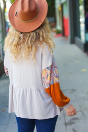 White peplum top with colorful patchwork sleeves and orange hat