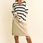 Woman in black white striped v-neck long-sleeve sweater, beige pants, brown suede boots
