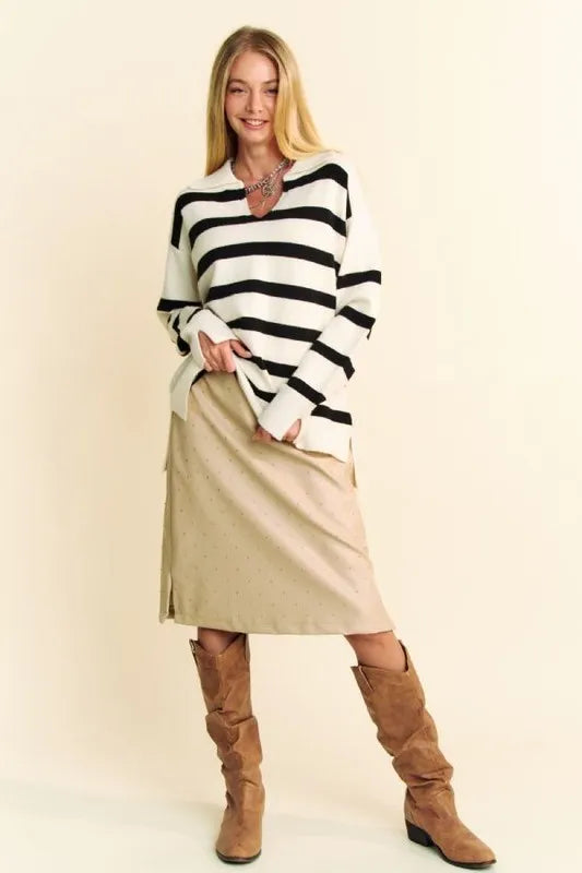 Woman in black white striped v-neck long-sleeve sweater, beige pants, brown suede boots