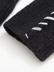 Black knit fingerless gloves with white feather design on sweater