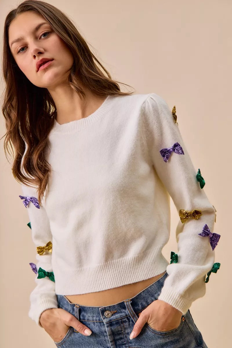 White SO ME Mardi Gras knit sweater with colorful sequined bows on sleeves