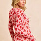 Pink long-sleeved BiBi button down shirt with red heart print and ruched front