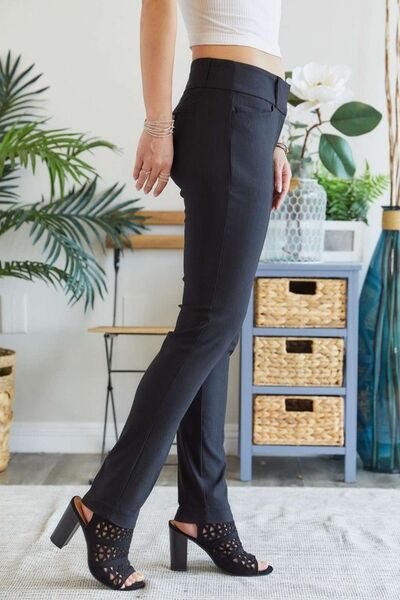 Shop Bottoms-A women wearing a pair of black straight leg pands and block heeled shoes with open toes.