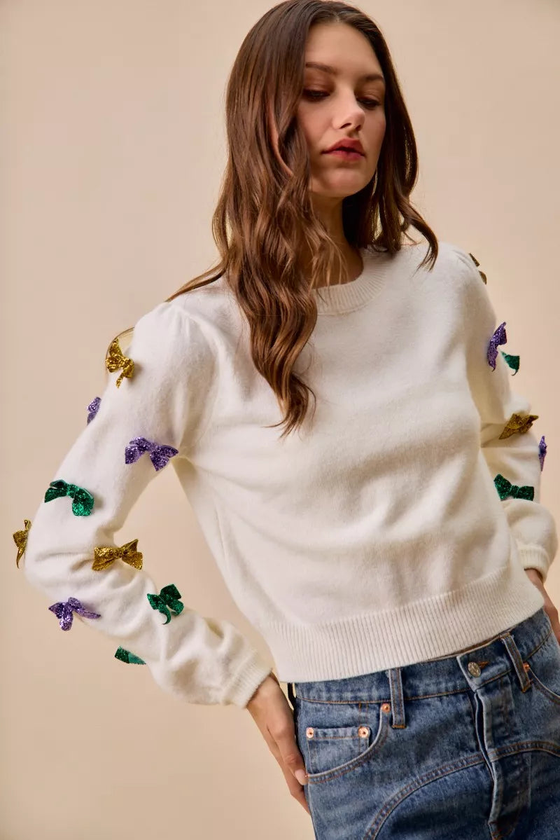 Cream-colored knit sweater with Mardi Gras sequined bows on sleeves