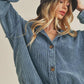 Woman wearing a blue denim jacket and black bucket hat against a beige background