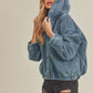 Woman wearing a blue denim jacket against a beige background