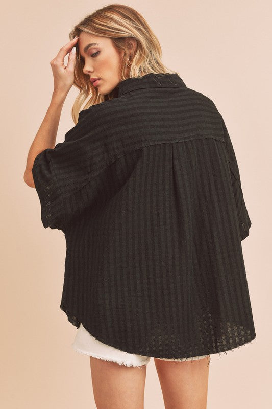 Black ribbed knit blouse by Aemi + Co with relaxed fit, frayed hem