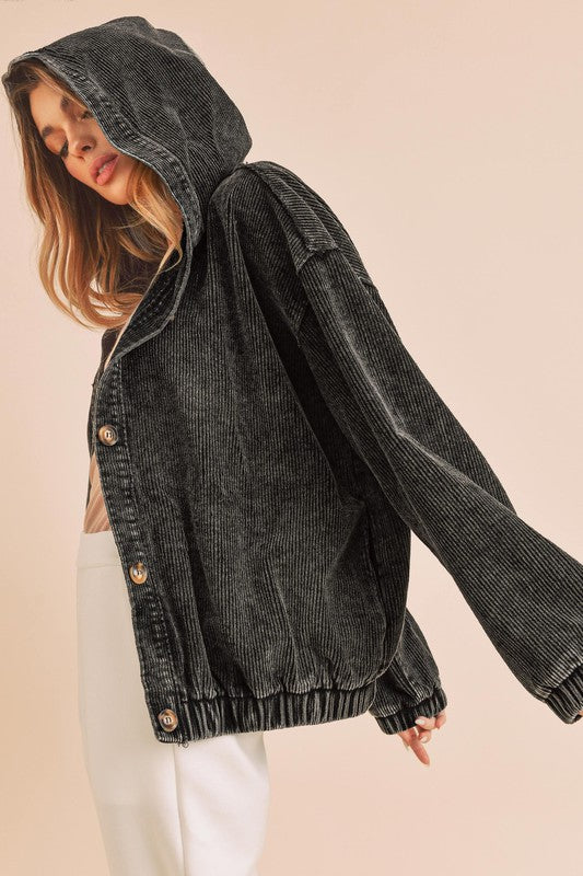 Black corduroy jacket worn by a person on a beige background