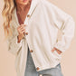 Woman wearing a white corduroy jacket with brown buttons on a beige background