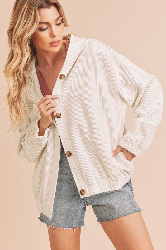 Woman wearing a white corduroy jacket with brown buttons on a beige background
