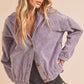 Woman wearing a purple corduroy jacket and black shorts on a beige background