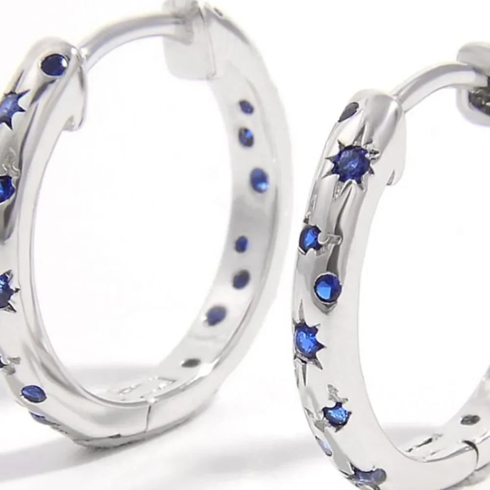 Silver starry huggie earrings with blue zircon gemstones