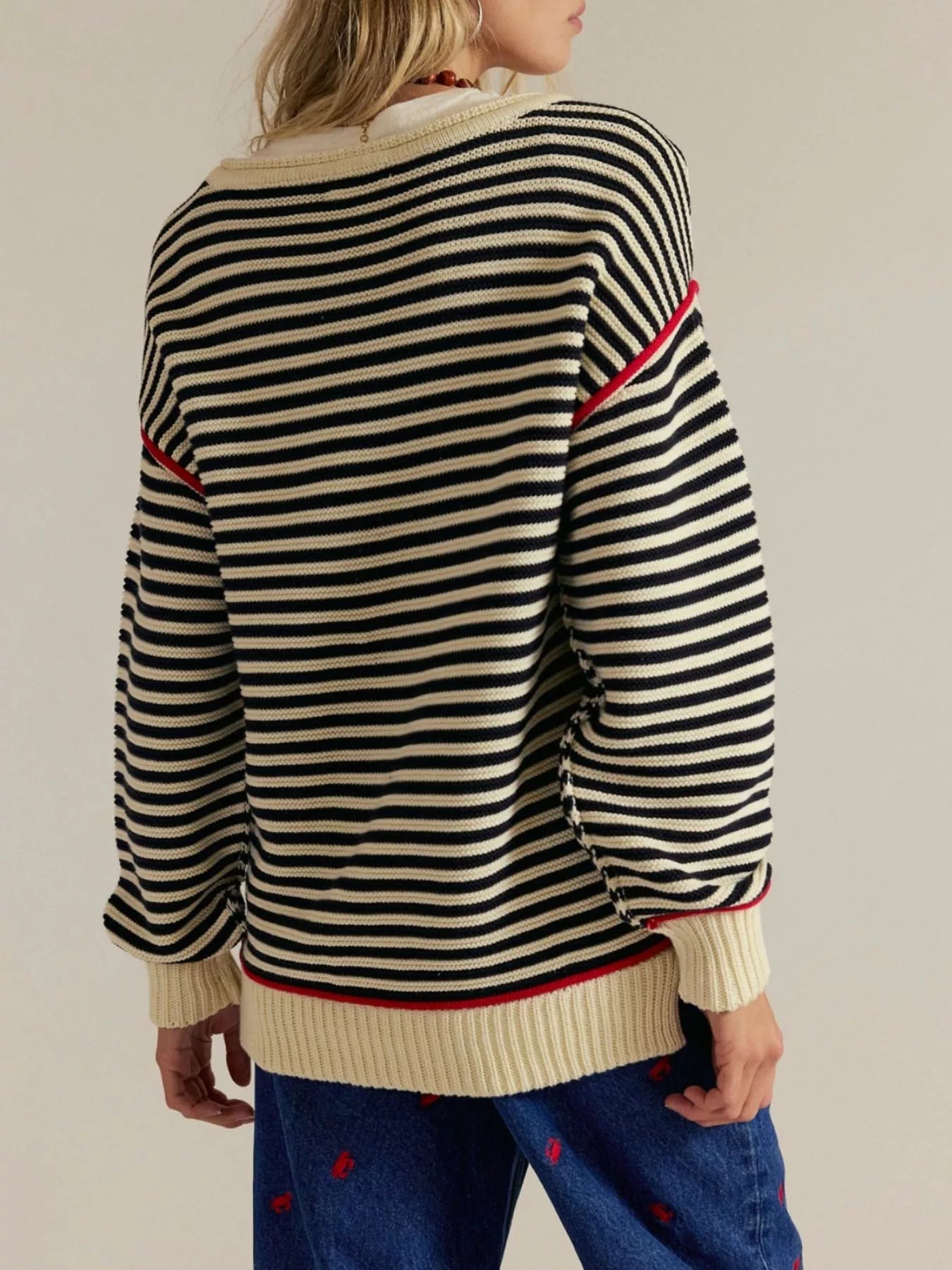 Black and cream striped knit sweater with red trim on sleeves, hem, and cuffs
