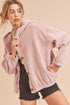 Woman wearing a pink corduroy jacket and black shorts on a beige background