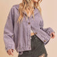 Woman wearing a purple corduroy jacket and black shorts on a beige background