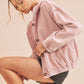 Woman wearing a pink corduroy jacket on a beige background