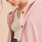 Woman wearing a pink striped shirt with wooden buttons on a beige background