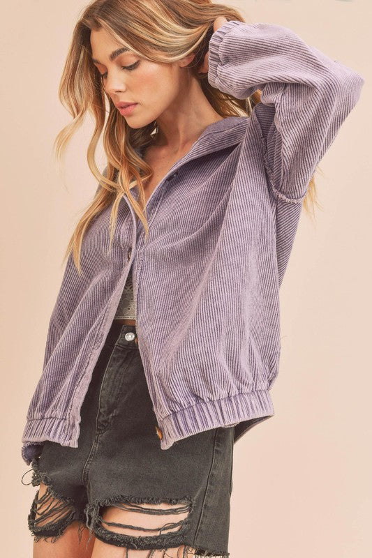 Woman wearing a purple corduroy jacket against a beige background