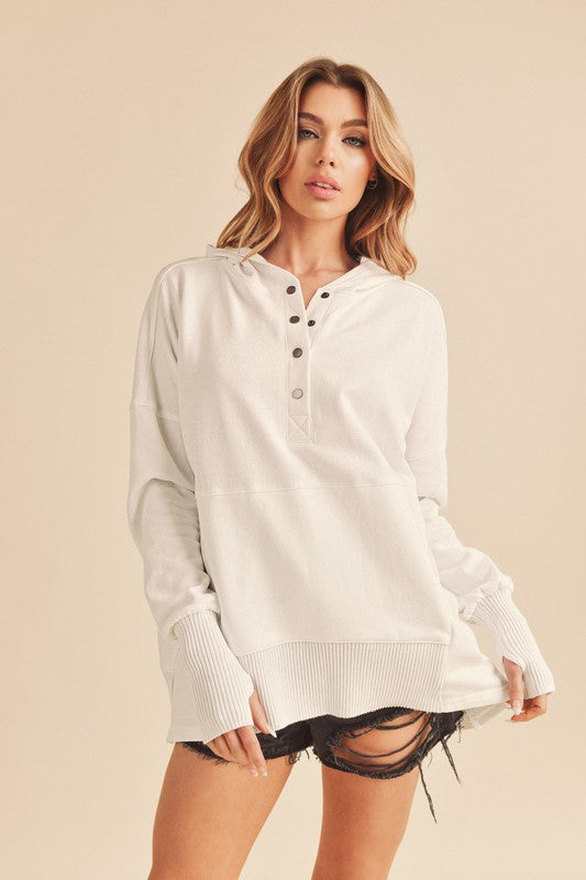 Woman wearing a white long-sleeve hoodie against a beige background