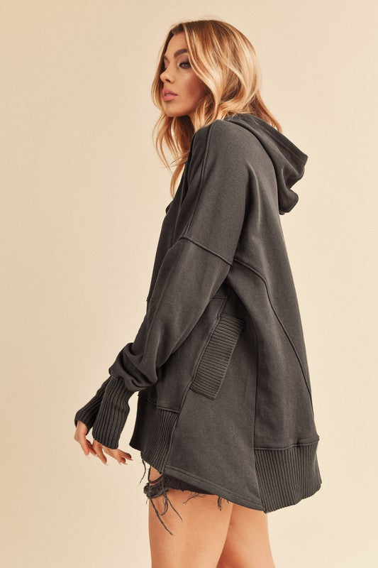 Woman wearing a dark gray hoodie on a beige background