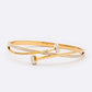 A gold-colored stainless steel bangle bracelet with crystal pave nail accents.