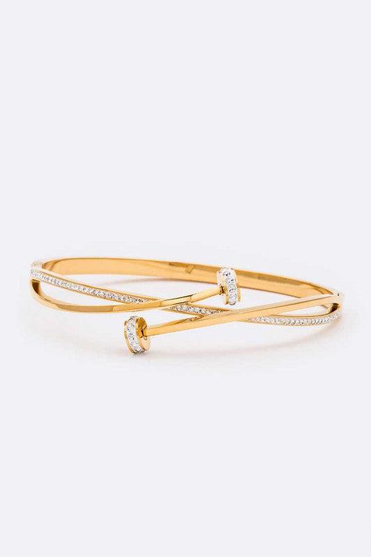 A gold-colored stainless steel bangle bracelet with crystal pave nail accents.
