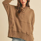 Woman wearing a brown hoodie and denim shorts against a beige background