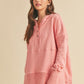 Woman wearing a pink long-sleeve hoodie against a beige background