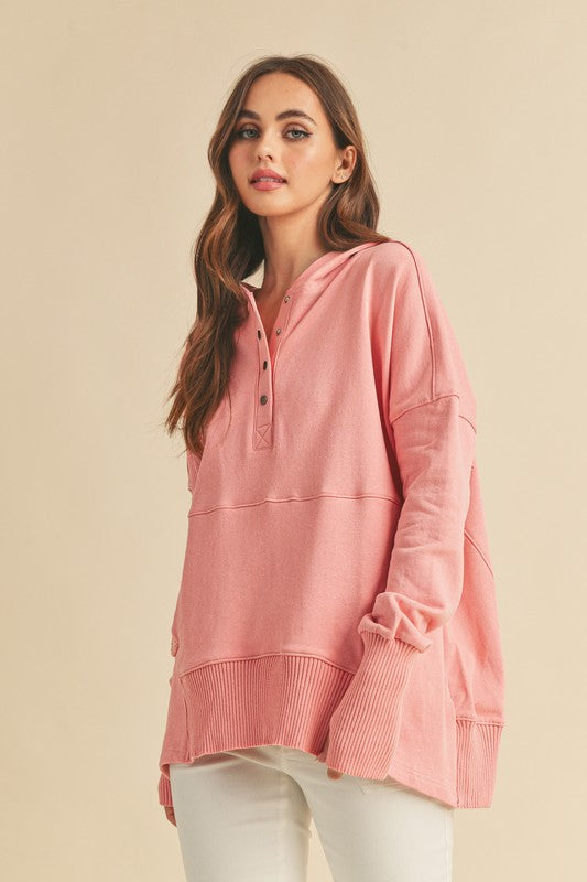 Woman wearing a pink long-sleeve hoodie against a beige background
