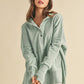 Woman wearing a light green hoodie and white pants on a beige background