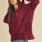 Woman wearing a burgundy hoodie and light blue jeans on a beige background