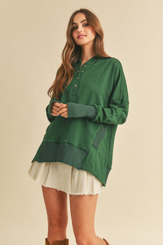 Woman wearing a green long-sleeve hoodie and white skirt on a beige background