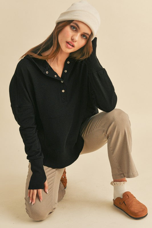 Woman wearing a black long-sleeve hoodie, beige pants, and brown shoes on a beige background
