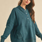 Woman wearing a teal hoodie against a beige background