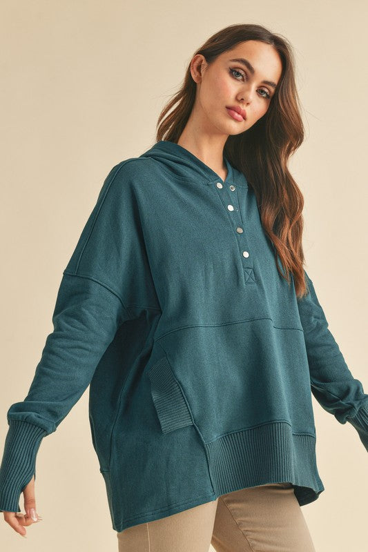 Woman wearing a teal hoodie against a beige background