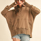 Woman wearing a brown oversized hoodie and denim shorts on a beige background