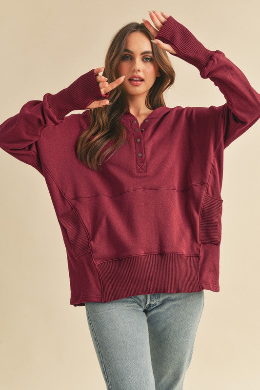 Woman wearing a burgundy hoodie with a beige background