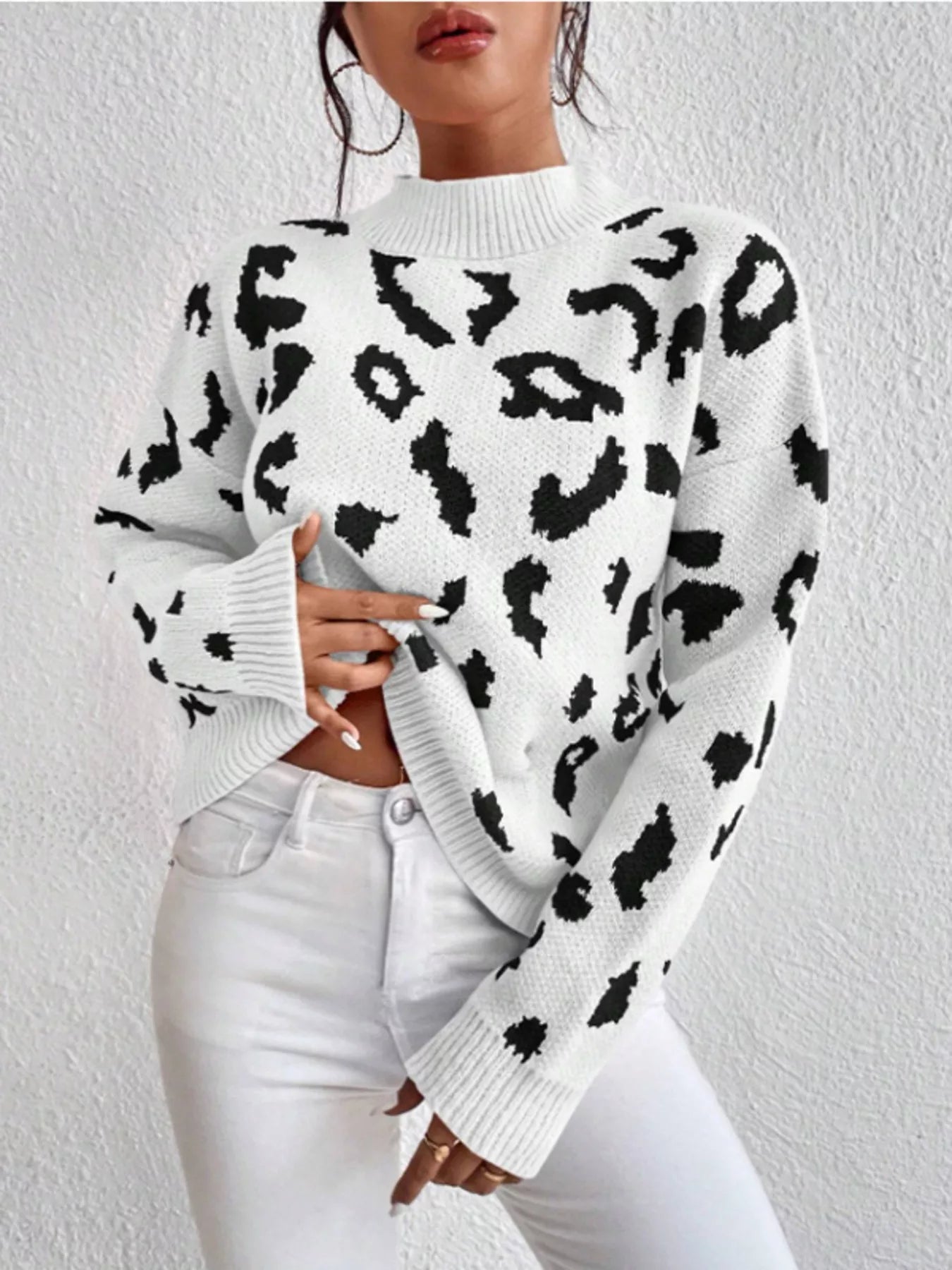 Leopard print mock neck sweater with black spots on white knit fabric