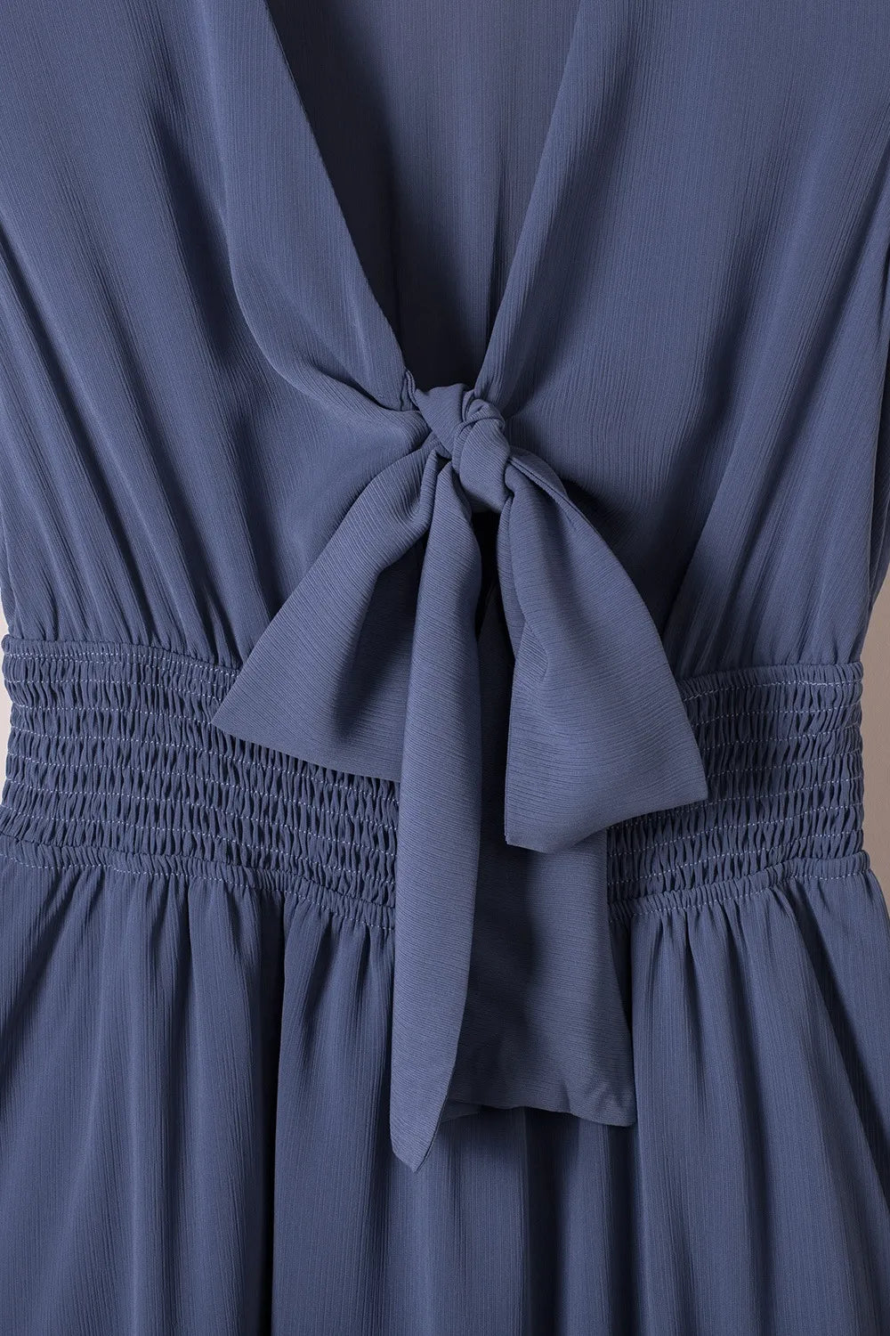 Tie-front mini dress in soft blue with smocked waist and back bow