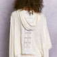 Cream ribbed knit poncho with white floral embroidery and frayed hem
