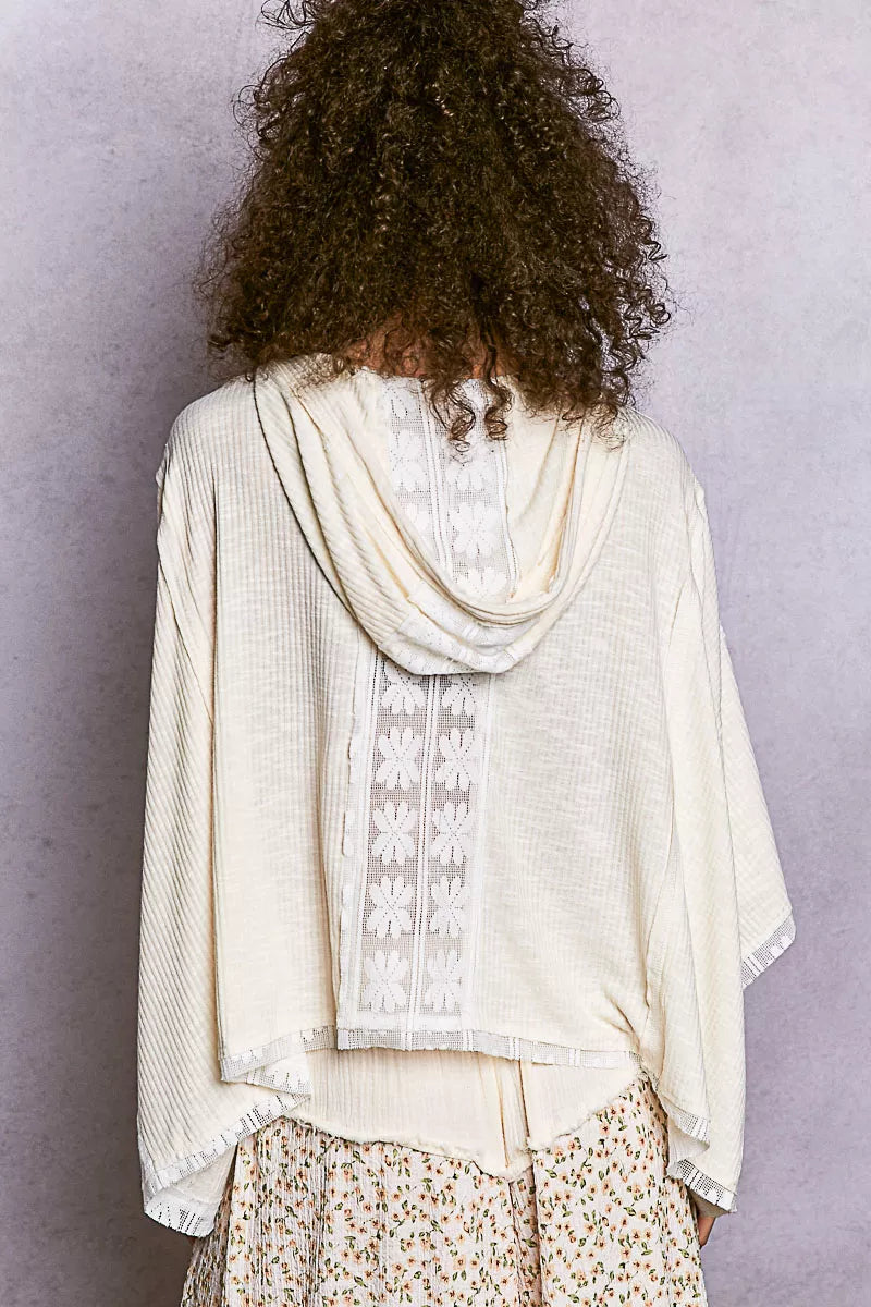 Cream ribbed knit poncho with white floral embroidery and frayed hem