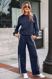 Woman wearing a navy tracksuit with white stripes standing on a sidewalk.