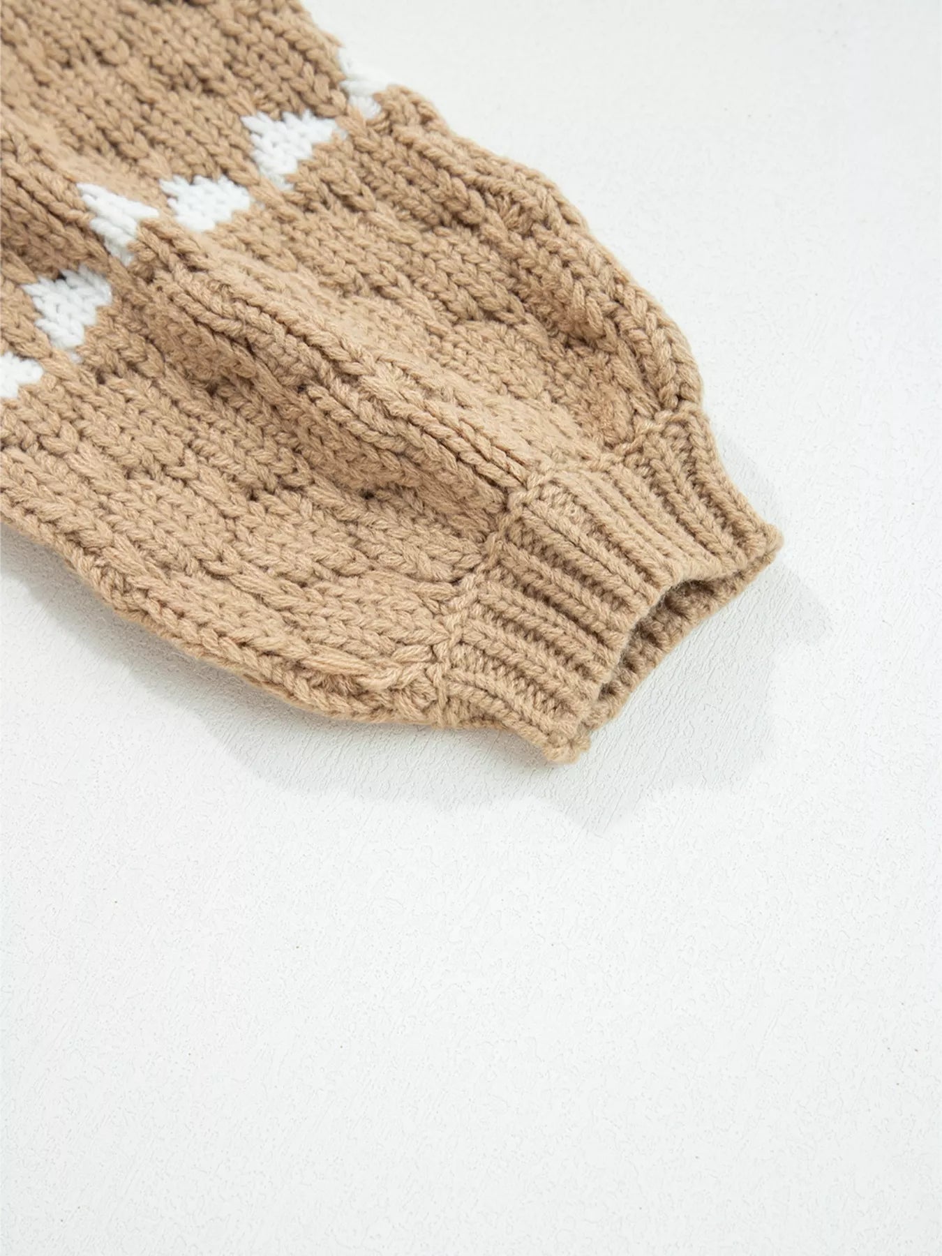 Beige textured knit sweater sleeve with white diamond patterns and ribbed cuff