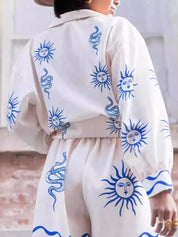 White and blue sun face print jumpsuit with snakeskin belt by Daverri Fashions